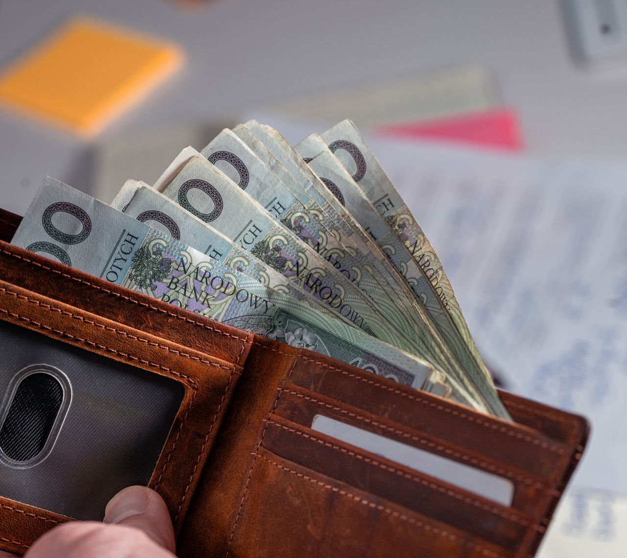 Portfel z banknotami i dokumenty rozliczeniowe na biurku